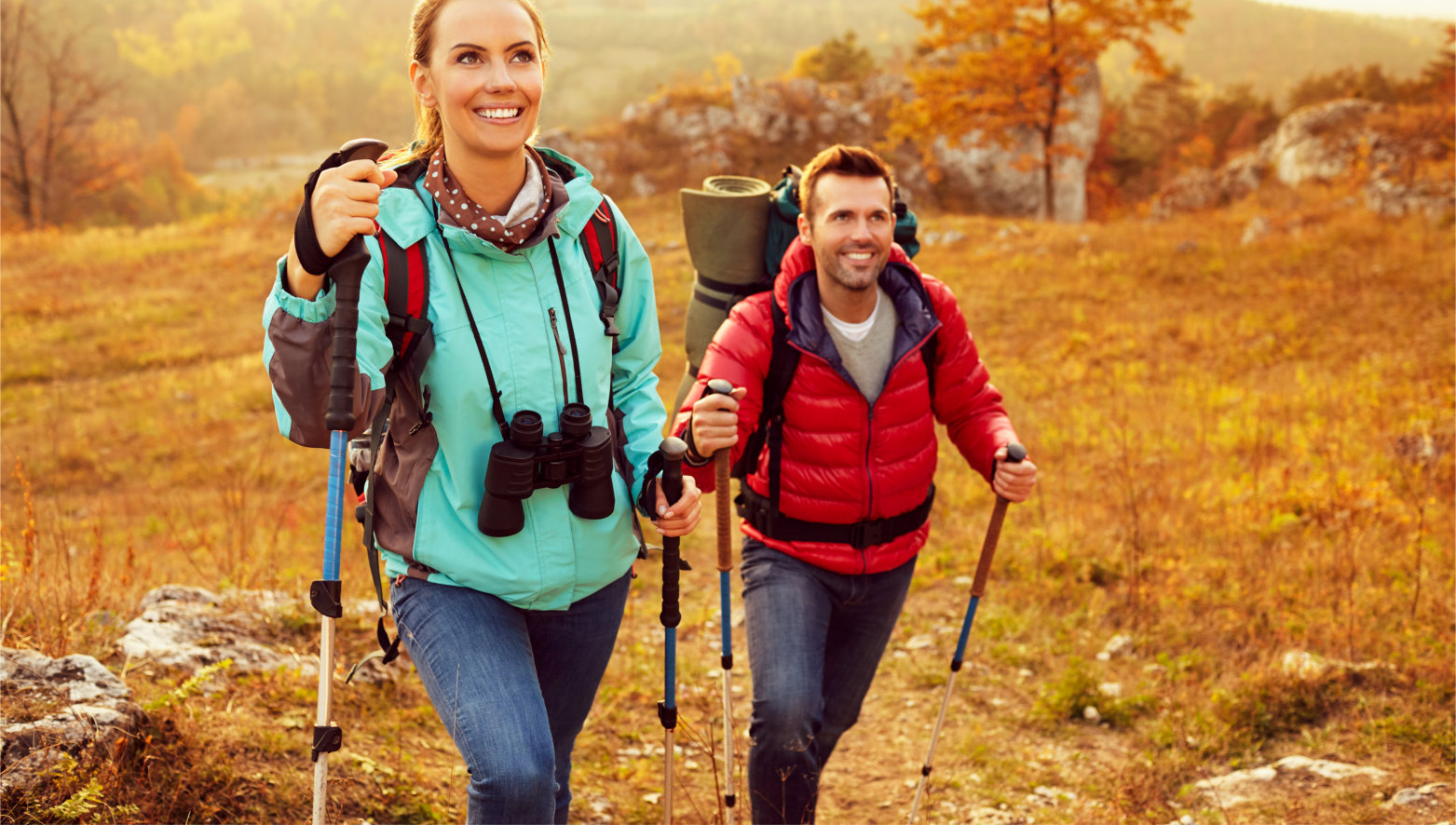 Couple,Hiking,During,Autumn,Vacation,With,Sticks,And,Backpacks
